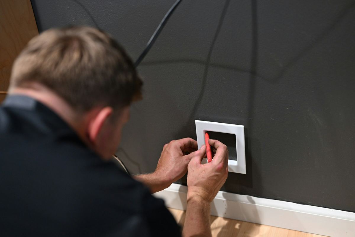 Elektricien plaatst een inbouwraam voor een schakelaar in een donkere muur